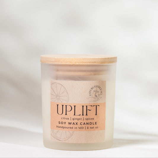 Candle with 'Uplift' label on a soft white background
