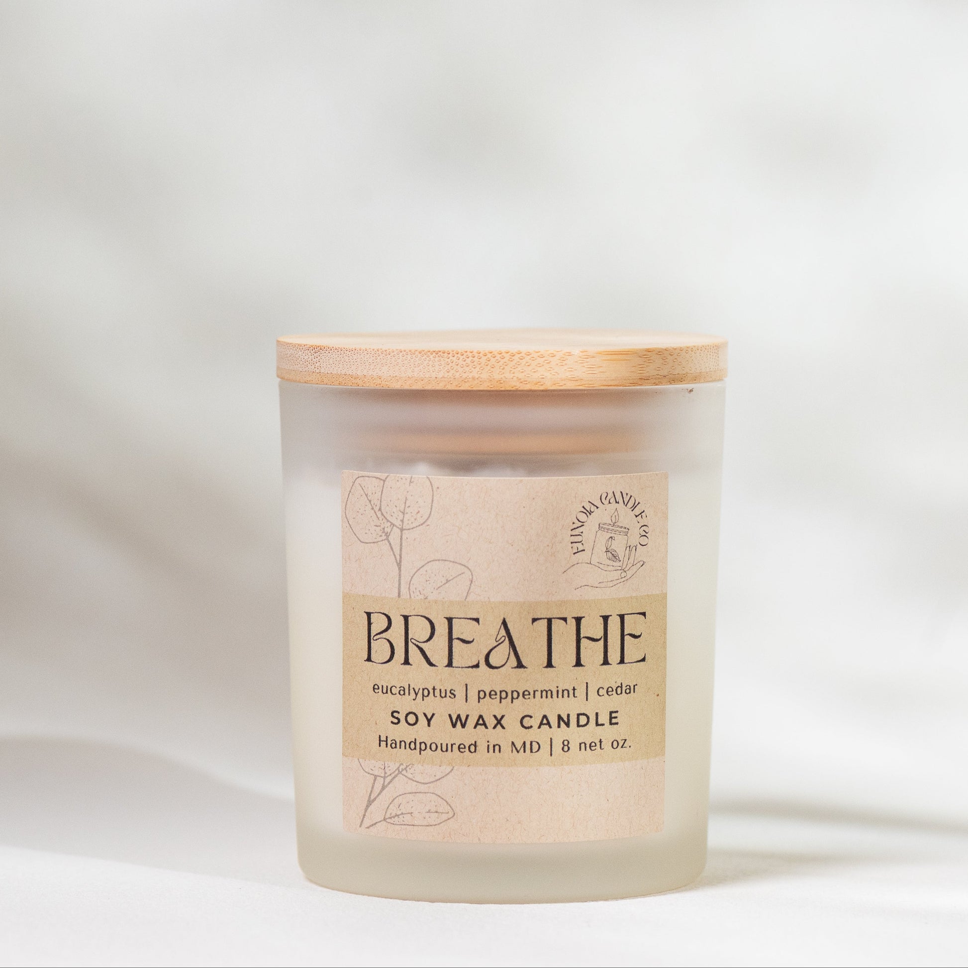 Candle labeled 'Breathe' on a soft white background