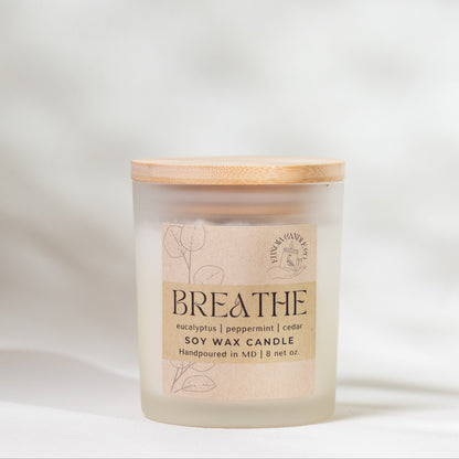 Candle labeled 'Breathe' on a soft white background