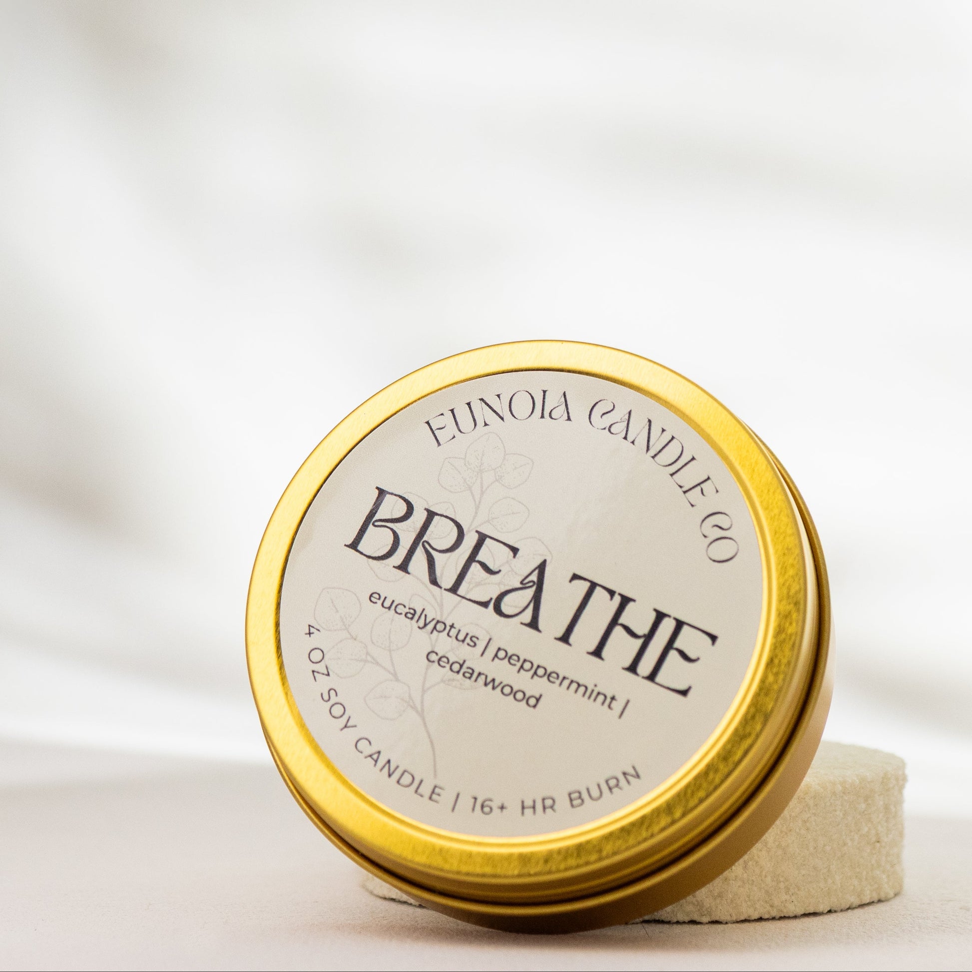 gold Candle tin labeled 'Breathe' by Eunoia Candle Company on a soft white background