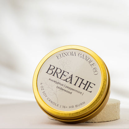 gold Candle tin labeled 'Breathe' by Eunoia Candle Company on a soft white background