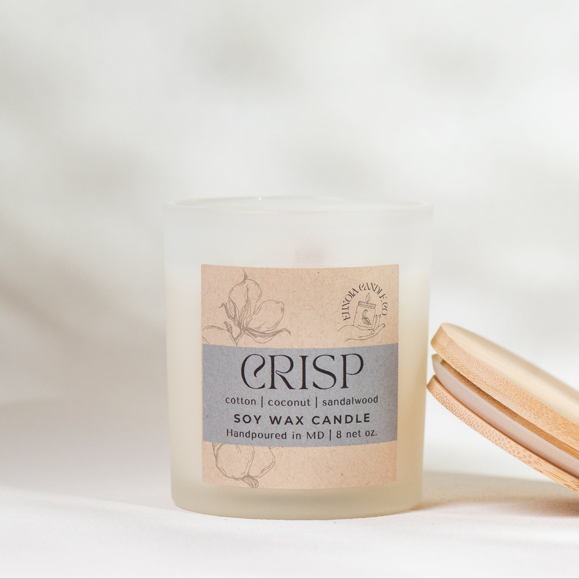 Crisp soy wax candle with wooden lid on a soft white background