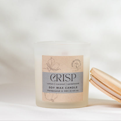 Crisp soy wax candle with wooden lid on a soft white background