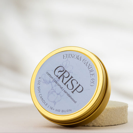 Gold tin labeled 'CRISP' on a soft white background by Eunoia Candle Company
