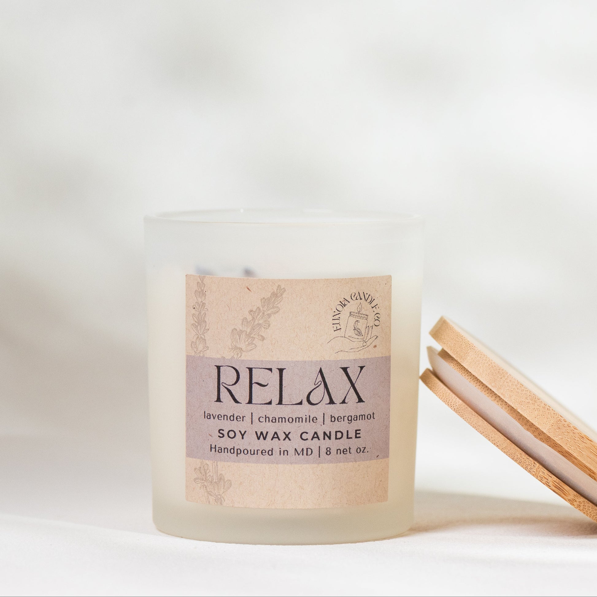 Candle with 'relax' on kraft paper label and a wooden lid on a white background