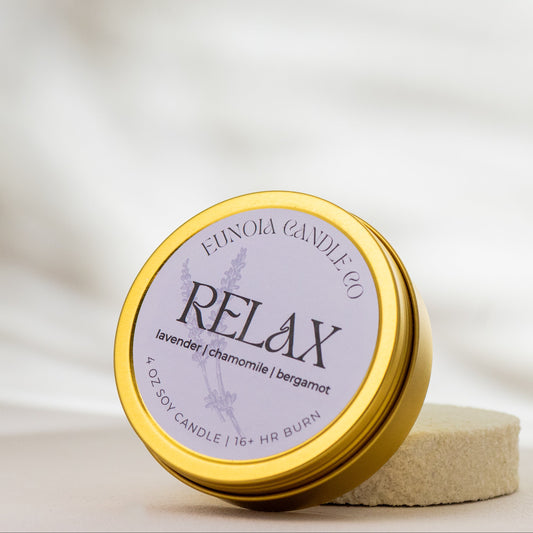 Candle jar labeled 'Relax' by Eunoia Candle Co on a soft white background