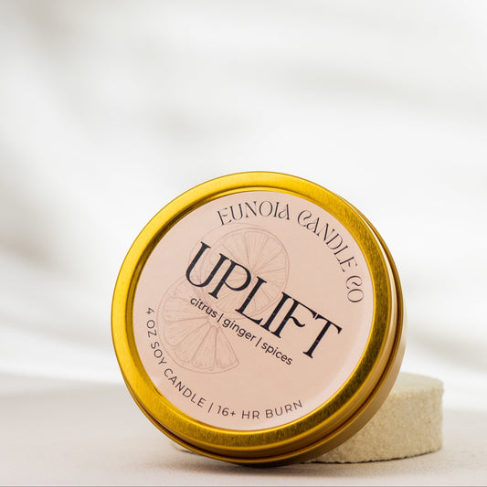 Candle jar labeled 'Uplift' by Eunoia Candle Co. on a white background