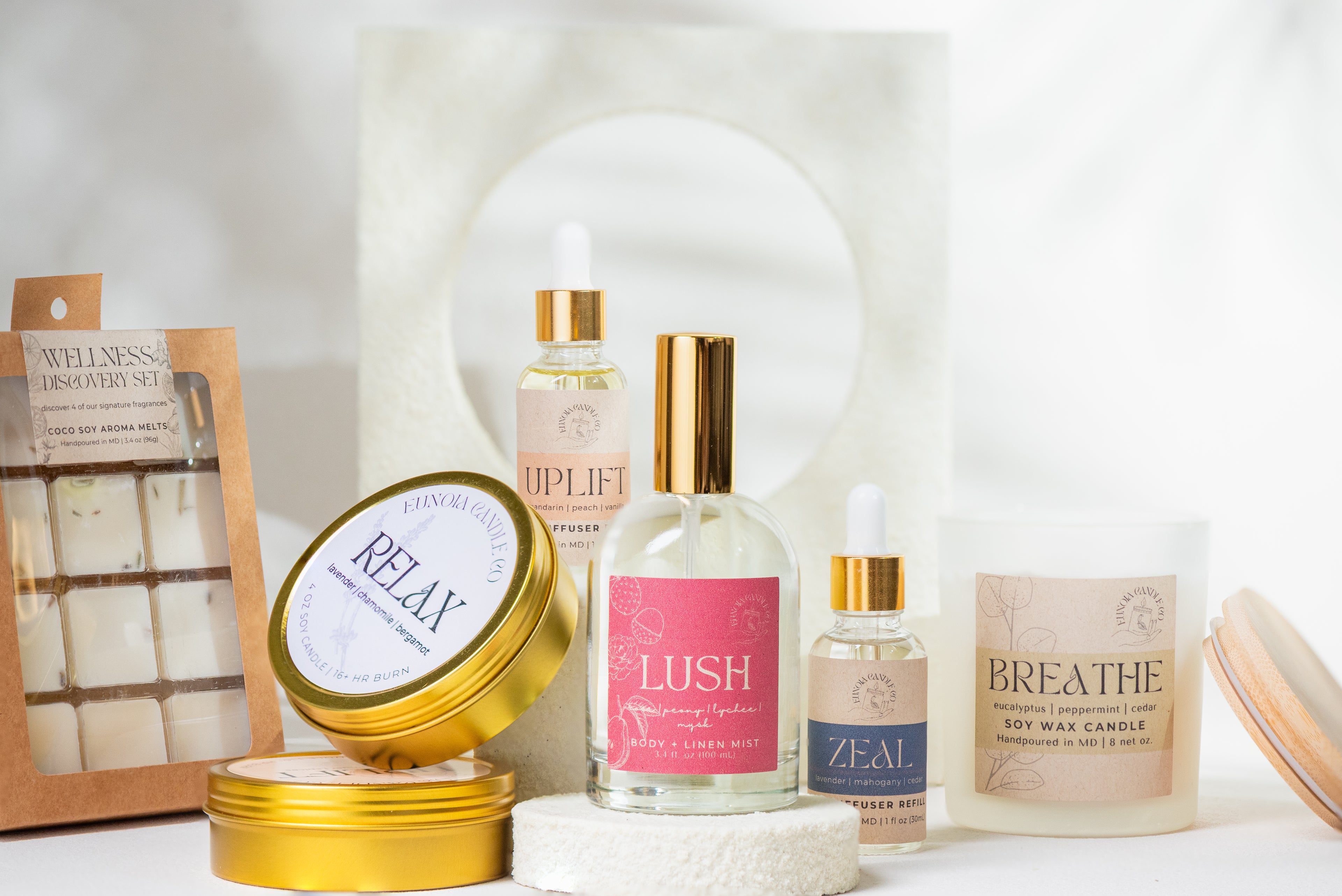 Collection of wellness products including candles and diffusers on a white surface.